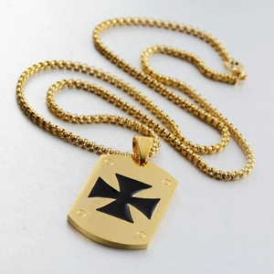 Detail shot of golden dog tag pendant with black iron cross and decorative screws