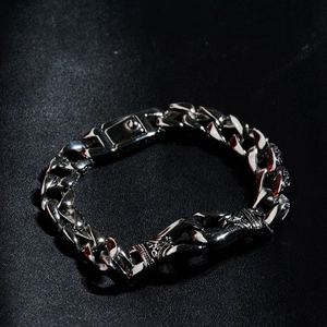Detail of silver stainless steel Cuban link bracelet with Gothic engraved clasp on leather
