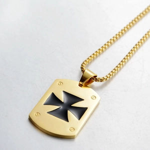 Macro detail of gold rectangle pendant with black cross emblem and box chain