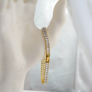 Detail of gold-plated tennis bracelet featuring rectangular cubic zirconia and fold-over clasp