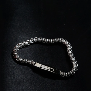 Bracelet chaîne à mailles carrées en acier inoxydable argenté sur surface en cuir noir