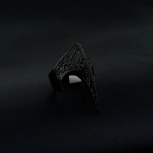Detail of gothic black claw ring with embossed pattern on dark leather background