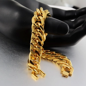 Macro detail of thick gold Cuban link chain with square slide clasp on hand model