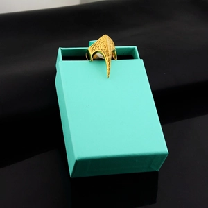 Detail showing the intricate gold eagle claw ring on a premium turquoise jewelry box