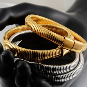 Detailed view of three polished metal snake bone bracelets in gold and silver finishes