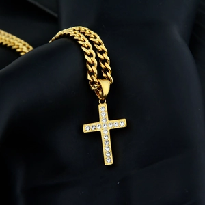 Makroaufnahme von Gold-Kreuzanhänger mit Kristallen an einer dicken Panzerkette