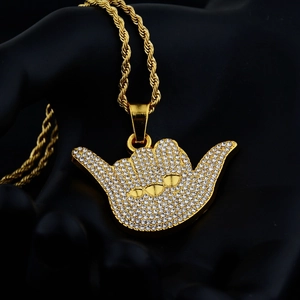 Vista macro del ciondolo a mano shaka hip hop dorato con strass e catena a corda intrecciata
