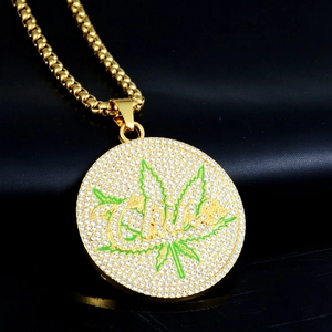 Détail macro du pendentif hip hop plaqué or avec strass blancs et design de feuille verte