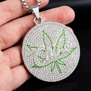 Vue macro d'un grand pendentif hip hop argenté avec strass et motif de feuille verte