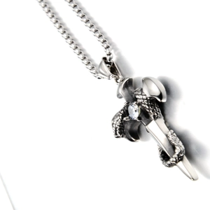 Gothic style necklace featuring a coiled snake on a cross with a round white gemstone