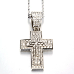 Détail macro du pendentif croix glacé avec cristaux pavés sur une chaîne torsadée argent