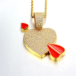 Macro shot of a gold iced-out heart and arrow pendant on a twisted rope chain necklace
