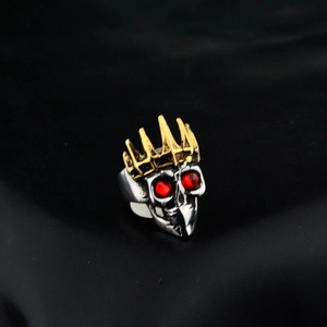 Gothic skull ring with a golden crown and red crystal eyes on black leather background