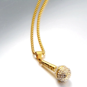 Detailed close-up of golden microphone pendant necklace with sparkling white rhinestones