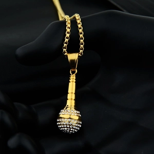 Detailed view of gold microphone pendant with pave white zircons on black hand model
