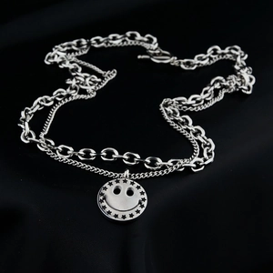 Close-up of double-layer titanium necklace featuring chunky Cuban links and star-eyed smiley pendant