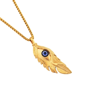 Close-up of golden feather pendant with blue evil eye detail on box chain necklace