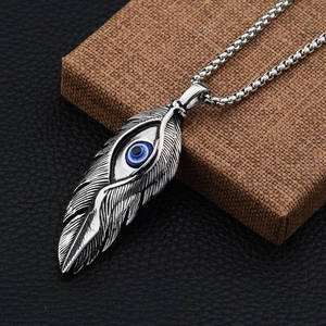 Close-up of hip hop feather pendant with blue eye detail on silver box chain