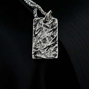 Macro shot of vintage steel pendant with rock lava texture and silver chain