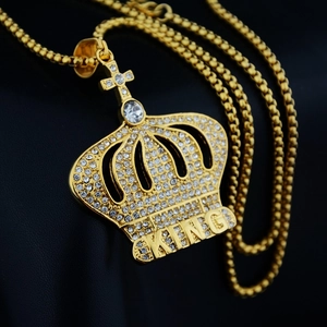 Dettaglio del ciondolo corona d'oro con strass e incisione KING su catena a maglia quadra