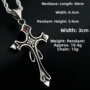 Gros plan du pendentif croix gothique avec pierre rouge et chaîne torsadée argentée