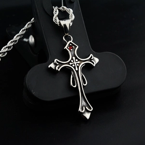 Vue macro du pendentif croix gothique avec pierre rouge et chaîne en acier noir