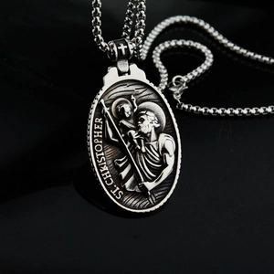 Détail du pendentif ovale Saint Christophe au fini argent vieilli sur fond de miroir noir