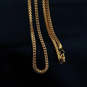 Collana a catena grano in oro lucido con chiusura a moschettone su sfondo scuro