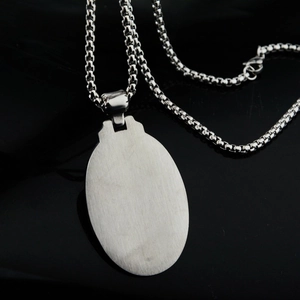 Gros plan d'un pendentif ovale en acier inoxydable argenté avec texture brossée et chaîne