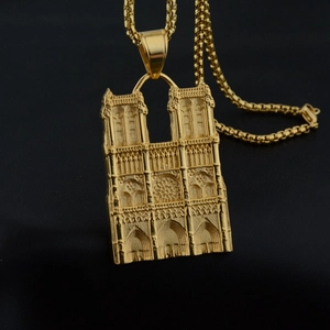 Detailed close-up of golden gothic cathedral relief pendant on a box chain necklace