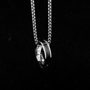Macro detail of intertwined ring pendants with Eternity engraving and black inner ring