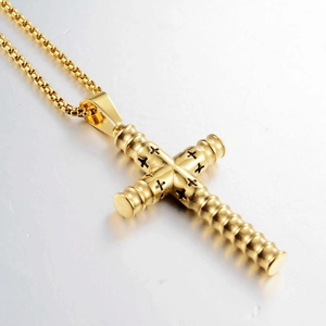 Makroaufnahme von goldenem Zylinder-Kreuzanhänger mit schwarzen Gravuren auf Perlenkette