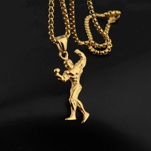 Dettaglio di un ciondolo da bodybuilder dorato su una catena a scatola per uomini