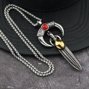 Detail of horn pendant necklace with red gemstone and silver feather on marble