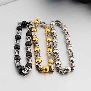 Vista dettagliata dei bracciali con perline in acciaio al titanio nero, oro e argento