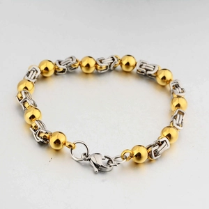 Dettaglio della catena bizantina argento e perle dorate lucide su bracciale in acciaio