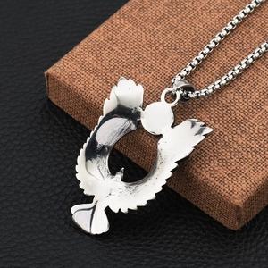 Gros plan du pendentif aigle argenté sur chaîne box sur fond de cuir noir