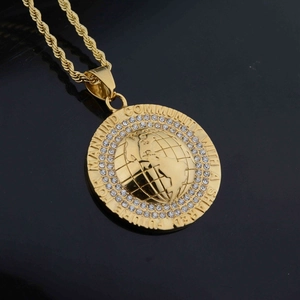 Macro shot of gold world map pendant necklace with crystal inlay and twist chain