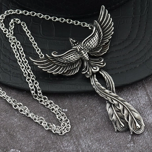 Close-up of vintage silver phoenix pendant with detailed feathers on a black leather background
