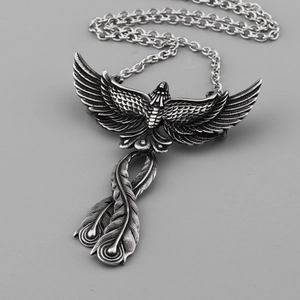 Detailed macro view of vintage silver phoenix pendant with intricately carved wings and tail