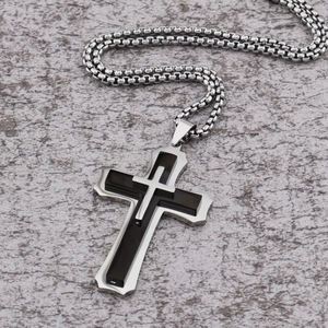 Detail of a double-layered cross pendant with black inlay on a stainless steel box chain