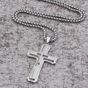 Detailed macro view of triple-layered silver stainless steel cross pendant and bead chain