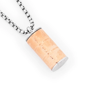 Dettaglio del ciondolo a cilindro in oro rosa con motivi in rilievo su catena a maglia quadra