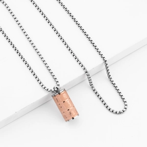 Dettaglio del ciondolo a cilindro in oro rosa con rilievo di loto e mantra su catena box