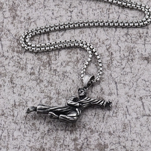 Macro view of vintage silver martial arts pendant showing detailed kick pose on a box chain