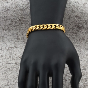 Nahaufnahme eines goldenen Panzerarmbands mit polierter Oberfläche an einer schwarzen Hand