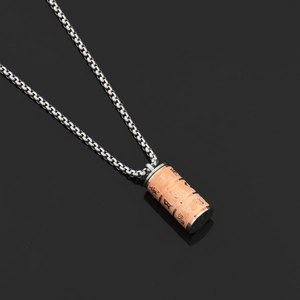 Dettaglio macro del ciondolo a cilindro rotante in oro rosa con mantra buddista e loto inciso