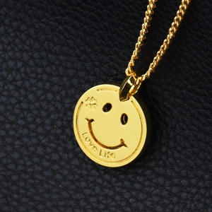 Détail macro du pendentif sourire doré avec gravure Love Life sur cuir noir élégant