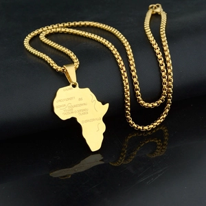 Macro detail of gold African map pendant with engraved letters on a black reflective surface