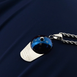 Macro shot of silver baseball cap pendant with Keep me warm engraving and twist chain